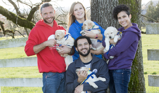 group of people holding Canine Companions puppies